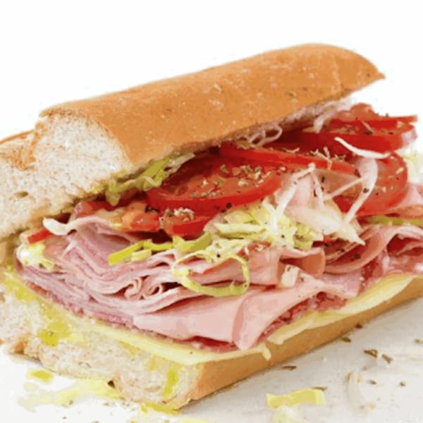 A large deli sub sandwich filled with meat, cheese, lettuce, tomatoes, and onions.